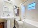 Bright bathroom featuring a classic pedestal sink and a shower with white tile surround at 923 Lexington St, Lakeland, FL 33801