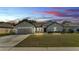 Charming single-story home with well-manicured lawn and two-car garage under sunset at 955 Hunters Meadow Ln, Lakeland, FL 33809