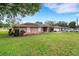 Exterior view of the brick home with a large lawn and driveway leading to an attached garage at 202 Saint Lucie Rd, Winter Haven, FL 33884