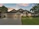 Charming single-story home with a manicured lawn, mature palm trees, and an attached two-car garage at 1342 Heritage Landings Dr, Lakeland, FL 33805