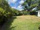 Green grass backyard with mature trees and partial fencing at 1528 Hallam S Ct, Lakeland, FL 33813