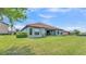 Lush green backyard showcasing a single-story home with a red tile roof and covered patio at 1983 Via Lago Dr, Lakeland, FL 33810