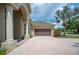 View of the home's front exterior featuring a two-car garage and lush tropical landscaping at 715 Hanover Ct, Lakeland, FL 33813