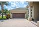 View of the home's front exterior highlighting a two-car garage and tropical landscaping at 715 Hanover Ct, Lakeland, FL 33813