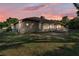 Backyard view of the brick home, offering a private outdoor space with lush greenery and a sunset sky at 7230 Hileman W Dr, Lakeland, FL 33810