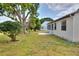 The backyard features a green lawn, mature trees, a concrete patio and screened-in porch at 1010 Penguin Pl, Lakeland, FL 33809