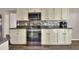 Updated kitchen featuring white cabinets, black appliances, stone backsplash, and wood-look flooring at 1010 Penguin Pl, Lakeland, FL 33809