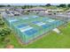 Aerial view of pickleball courts surrounded by a green fence and the community clubhouse with a pool in the background at 1010 Penguin Pl, Lakeland, FL 33809