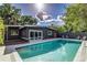 Outdoor pool area with clear blue water, gray home exterior, and lush foliage in a tropical setting at 1604 Sylvester Rd, Lakeland, FL 33803