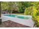 Swimming pool surrounded by lush foliage with a brick patio on a sunny day at 1604 Sylvester Rd, Lakeland, FL 33803