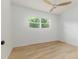 A bright bedroom with a ceiling fan, light wood floors, and a large window looking out to greenery at 1604 Sylvester Rd, Lakeland, FL 33803