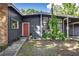 Charming single-story home with gray siding, red front door, large windows, and well-manicured front yard with lush landscaping at 1604 Sylvester Rd, Lakeland, FL 33803