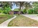 Picturesque home with mature trees, charming brick details, gray siding, and a welcoming walkway leading to the front door at 1604 Sylvester Rd, Lakeland, FL 33803