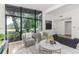 Elegant living room with floor-to-ceiling windows, modern furniture, white walls, and hardwood floors; bright and airy at 1604 Sylvester Rd, Lakeland, FL 33803