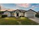 Attractive single-story home featuring a well-manicured lawn, an attached garage, and neat landscaping at 185 Heritage Park Ln, Mulberry, FL 33860