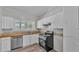 Bright kitchen featuring white cabinets, stainless steel appliances, and wood-look vinyl flooring at 2203 Avenue F Nw, Winter Haven, FL 33880