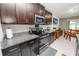 Modern kitchen with dark wood cabinets, granite countertops, and stainless steel appliances and a dining area at 2726 Red Egret Dr, Bartow, FL 33830