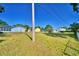 Large, grassy backyard showcasing ample space, a wooden pole, and distant views of neighboring homes at 2836 Magnolia Ave, Lakeland, FL 33812
