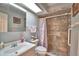Bright bathroom with a sink, toilet, and tiled shower featuring a floral shower curtain and grab bar at 2836 Magnolia Ave, Lakeland, FL 33812