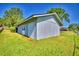 Exterior view of a small shed with a door, complemented by green grass and surrounding trees at 2836 Magnolia Ave, Lakeland, FL 33812