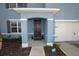 Covered front entrance with gray door, trimmed pillars, and manicured landscaping at a lovely two-story home at 3882 Resting Robin Ave, Bartow, FL 33830