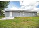 Backyard showcases the grey exterior, a white door, and a well-maintained lawn at 4215 Sunnyside Dr, Lakeland, FL 33810