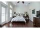 Bright bedroom features a comfortable bed, dark hardwood floors, a ceiling fan, and natural light at 460 Canterwood Dr, Mulberry, FL 33860