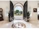View from the foyer looking out to the fountain and lush landscaping through iron double doors at 460 Canterwood Dr, Mulberry, FL 33860