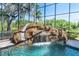 Enclosed pool featuring a waterfall, a slide, and lush landscaping beyond the screen at 460 Canterwood Dr, Mulberry, FL 33860