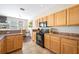 Well-lit kitchen featuring wooden cabinets, tile floors, and a view into the adjacent dining area at 6506 Sedgeford Dr, Lakeland, FL 33811
