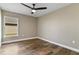 Neutral bedroom features wood-look floors, bright window, and a ceiling fan at 6625 Thornhill Rd, Winter Haven, FL 33880