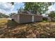 Exterior view of tan one-story home with a back door and green grass at 6625 Thornhill Rd, Winter Haven, FL 33880