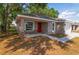 An eye-level exterior view of a single-story home featuring a manicured front yard and a red front door at 6625 Thornhill Rd, Winter Haven, FL 33880