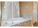 Bathtub with tile surround and curtained window in primary bathroom at 6626 Royal Forest Dr, Lakeland, FL 33811