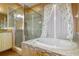 Primary bathroom featuring glass shower, soaking tub, wood look tile, and granite vanity at 6626 Royal Forest Dr, Lakeland, FL 33811
