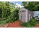 Outdoor storage shed nestled in a garden featuring lush greenery and a bed of red mulch at 6626 Royal Forest Dr, Lakeland, FL 33811