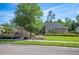 Attractive single-story home showcasing a well-maintained lawn, mature tree, and trimmed shrubbery at 6911 Wildberry Ln, Lakeland, FL 33813