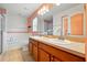 Bathroom featuring dual sinks, wood cabinets, tub with tiled wall, and large vanity mirror at 7139 Cedarcrest Blvd, Lakeland, FL 33810