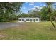 Inviting single-story home with palm trees, a large yard, and a gravel driveway at 7202 Glen Meadow Dr, Lakeland, FL 33810