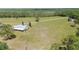 Scenic aerial shot of a home with a wraparound porch and a sprawling green field surrounded by trees at 8337 Fussell Rd, Polk City, FL 33868