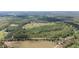 Aerial view showcases a large tract of land with a home, outbuildings, and interspersed wooded areas at 8337 Fussell Rd, Polk City, FL 33868