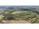 Scenic aerial view of a sprawling green field with a home and outbuildings in the distance at 8337 Fussell Rd, Polk City, FL 33868