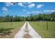 Long gravel driveway leading to a secluded property with mature trees and lush greenery at 8337 Fussell Rd, Polk City, FL 33868