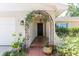 Inviting front porch with arched entry covered with flowering vines and brick steps at 1503 Clairdale Ln, Lakeland, FL 33801