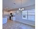 Open-concept kitchen and dining space features white cabinetry, modern lighting, and exterior views at 2303 Brassie Ct, Winter Haven, FL 33884