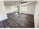 Bright living room featuring dark laminate flooring, a modern ceiling fan, and natural light from large windows at 2527 Dons Pl, Lakeland, FL 33801