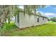 Side view of the house with green lawn, trimmed shrubs, and stucco wall at 505 Shanklin Ave, Bartow, FL 33830