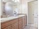 Bathroom with double vanity sinks, wood cabinetry, and an adjoining room at 5612 Vintage View Blvd, Lakeland, FL 33812