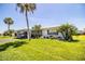 Single-story home showcasing lush green lawn, tropical landscaping, and a carport at 610 Cottage Ln, Lakeland, FL 33803