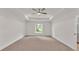 Large, carpeted bedroom with a tray ceiling, ceiling fan, and a window overlooking a tree lined yard at 803 Allison Place, Bartow, FL 33830